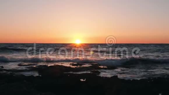 海浪拍打着橙色的日落太阳落山在美丽的大海上令人难以置信的橙色日落黄昏时的海洋海浪撞击视频的预览图