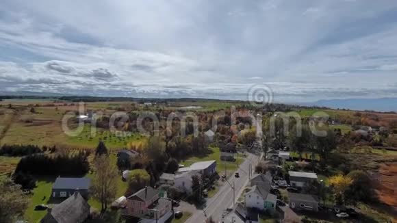无人机摄像机在一个绿色田野的村庄附近的一条有汽车的路上移动视频的预览图
