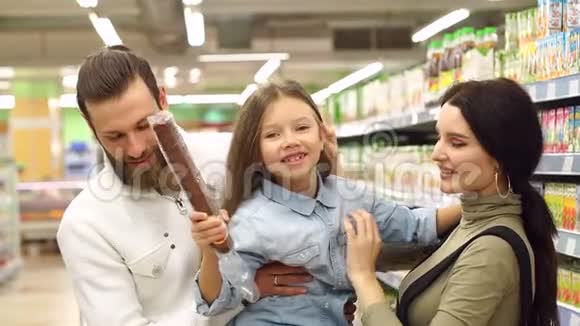 爸爸妈妈和女儿在商店买香肠爸爸把女儿抱在怀里视频的预览图