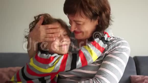 成熟的女人拥抱卷曲的少年男孩一个小学生的祖母和孙子家庭幸福祖母好母亲日子视频的预览图