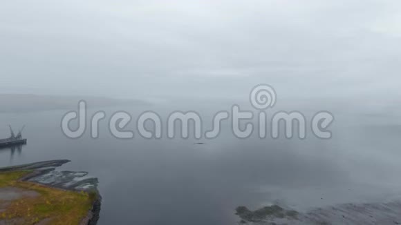 从江口浓雾的高空俯瞰岸边有一座黑山和一座码头视频的预览图