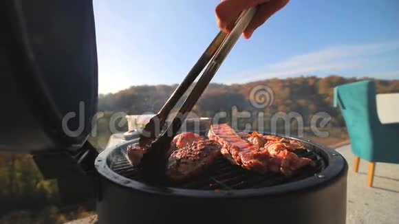 一块块肉鸡排骨火上煎厨师手翻着肉在屋顶烧烤肉视频的预览图