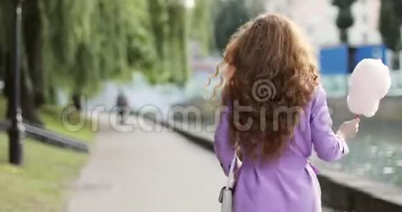 红发的快乐女孩在日落时带着棉花糖在夏日公园散步视频的预览图
