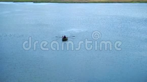 人们坐在有桨的船上在蓝湖里的船视频的预览图