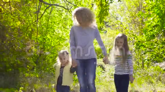 快乐的白种人一家人在秋天公园的树间散步微笑着的成年卷发女子手牵着她的手视频的预览图
