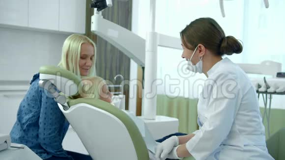 小女孩坐在牙科椅上妈妈和医生说话视频的预览图