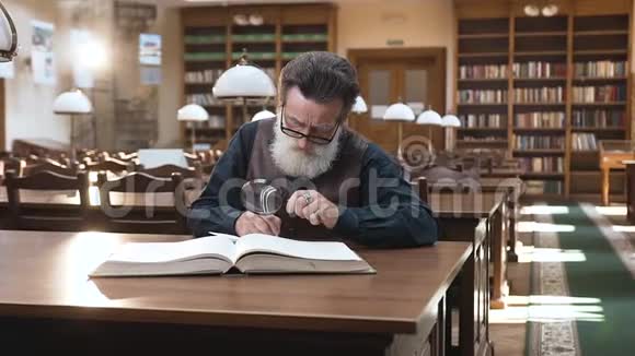 前景聪明的老人集中在眼镜里从书中记录重要的笔记坐在里面视频的预览图