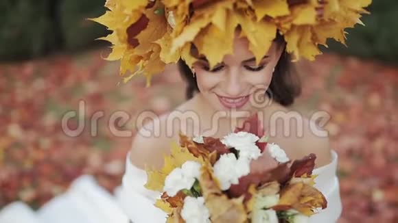 秋天公园的新娘快乐戴着鸭叶花环的女人新娘对着镜头微笑视频的预览图