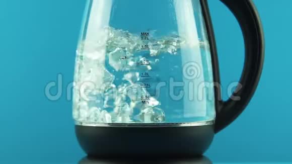 有玻璃墙的电热水壶沸腾的过程蓝色背景概念视频的预览图
