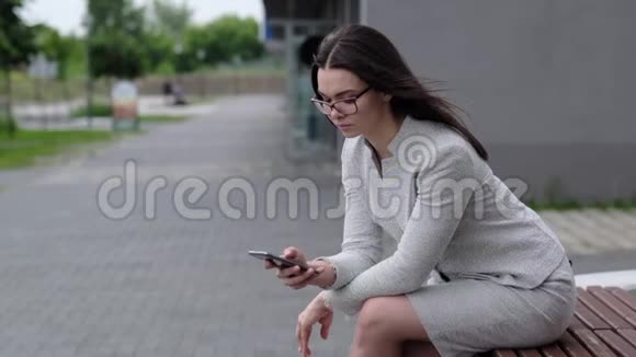 一个穿夹克和裙子的女孩在电话里读留言一个戴着眼镜的女商人在一个视频的预览图
