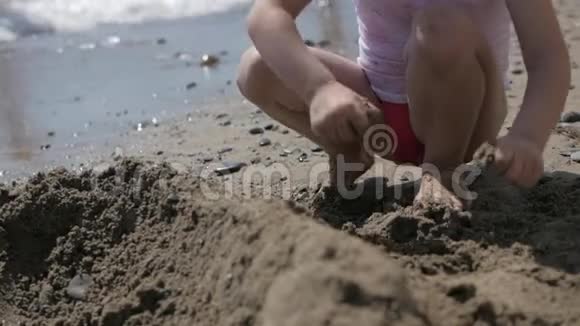 小可爱的女孩在海边的海滩上玩沙子视频的预览图