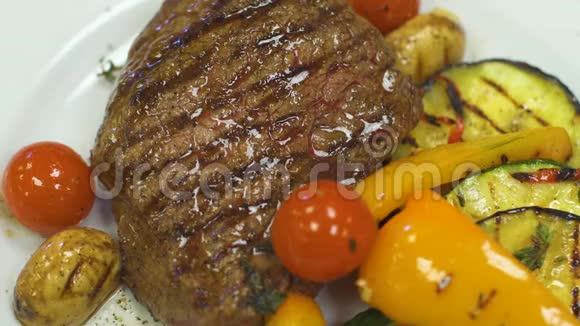 脂肪牛肉牛排放在一个白色盘子里上面有烤蔬菜视频的预览图