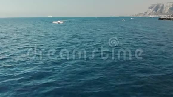 未被识别的游艇在电影中沿着蓝绿色的海水在岩石的背景下视频的预览图