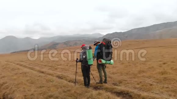 高山高原上戴着大背包戴着帽子戴着墨镜的一对旅人的鸟瞰图视频的预览图