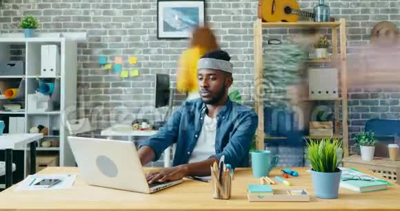 在办公室里用笔记本电脑工作的美国黑人商人视频的预览图