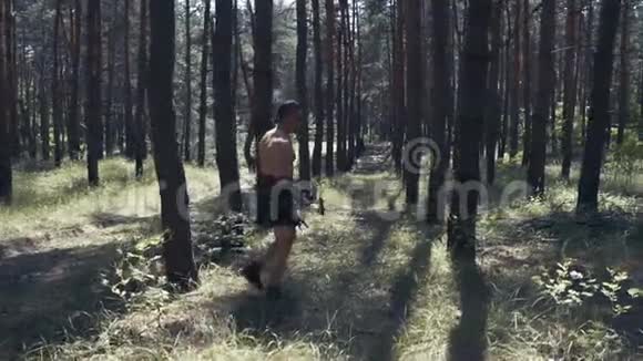 一个肌肉发达的野蛮战士正在树林里行走和磨刀视频的预览图