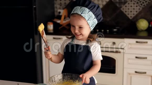 厨房里一个迷人的小女孩用木勺和面团的肖像视频的预览图