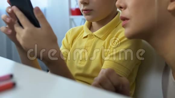 小男孩向妈妈展示智能手机的现代应用程序游戏成就视频的预览图