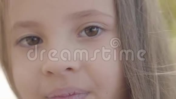 一个年轻漂亮的棕色眼睛女孩的特写黑发女孩对着镜头微笑无辜的白种人儿童视频的预览图