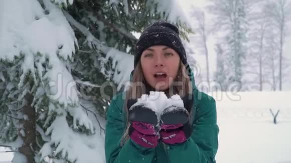 快乐的女人在森林里用手扔雪雪落在阳光下闪闪发光女孩在冬天玩耍视频的预览图