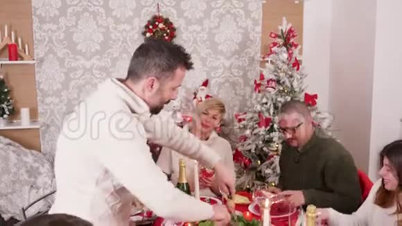 一家人笑着庆祝圣诞节一个人在切美味的火鸡视频的预览图
