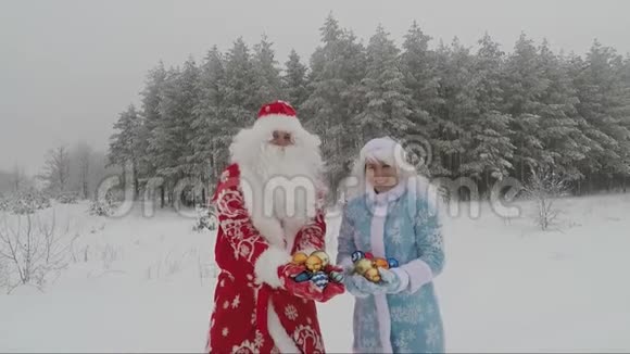快乐的圣诞老人和年轻的女孩在冬天的森林里投掷彩色圣诞球玩得很开心新年视频的预览图