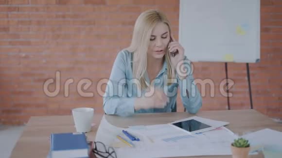 焦点女性金发经理在电话上交谈并比较平板电脑上的图表在办公室女商人视频的预览图
