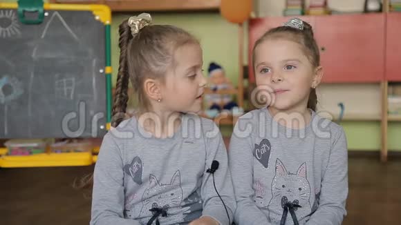坐在椅子上的双胞胎女孩回答问题女孩在课堂上接受采访的背景是视频的预览图