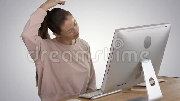 精疲力竭的年轻女性坐在家里的办公桌上在梯度背景下按摩脖子视频的预览图