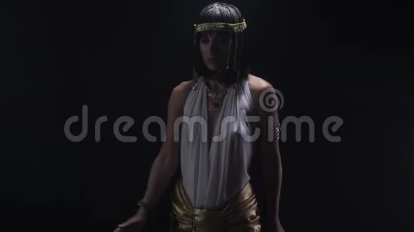 埃及艳后站在一个古埃及的姿势在戏剧性的灯光下视频的预览图