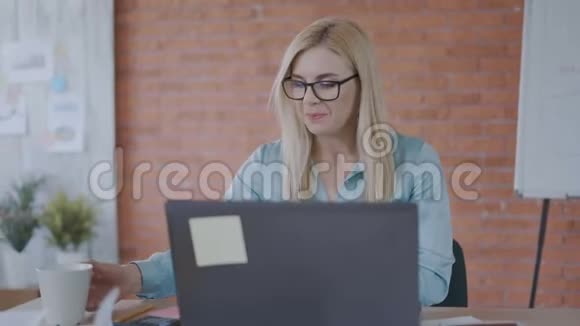 漂亮的女人35岁在午餐时喝咖啡在电脑办公室里工作压力很大成功视频的预览图
