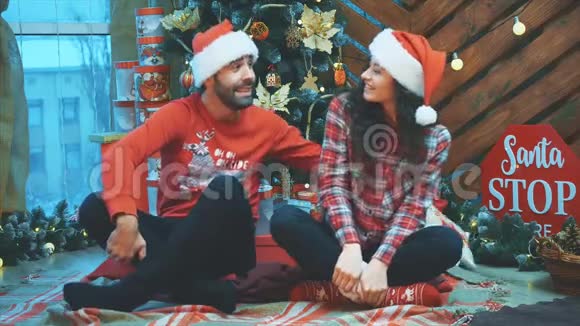 经典的新年树装饰男孩和女孩戴着圣诞帽男孩用枕头打他的女朋友视频的预览图