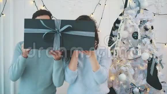 视频的人隐藏他们的脸在灰色的礼品盒后与条纹流光然后显示他们的脸并再次隐藏视频的预览图