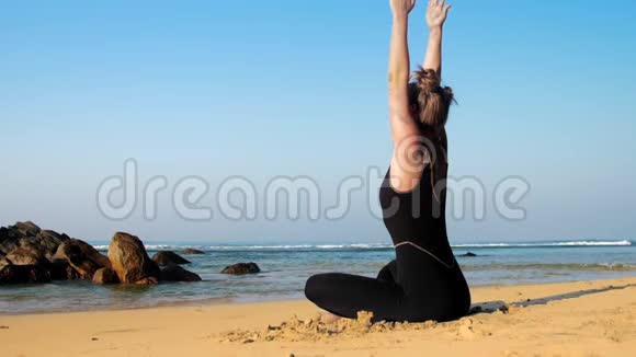 女士举手坐在沙滩上做瑜伽姿势视频的预览图