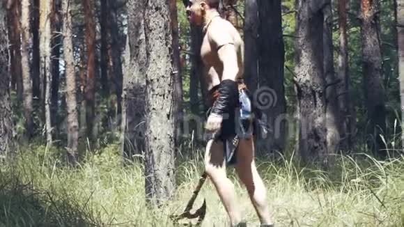一个身材赤裸的野蛮人正拿着斧头在森林里视频的预览图