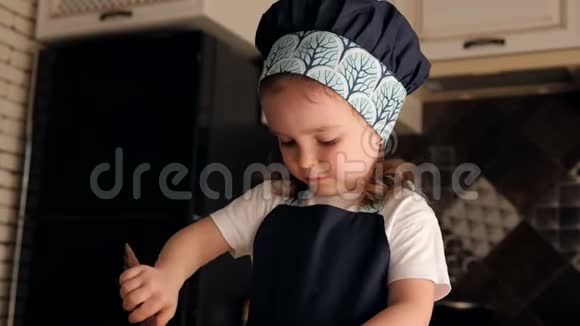 厨房里一个迷人的小女孩用木勺和面团的肖像视频的预览图