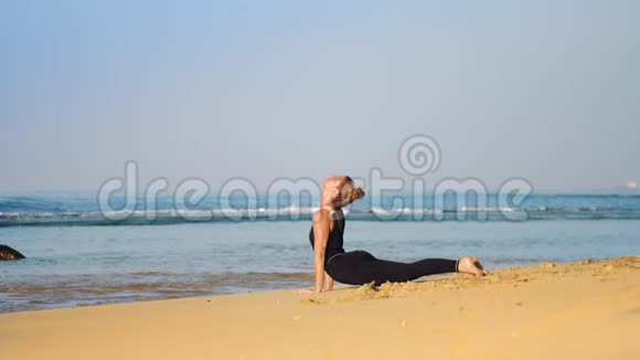 穿黑色运动服的金发女孩冥想瑜伽姿势眼镜蛇视频的预览图