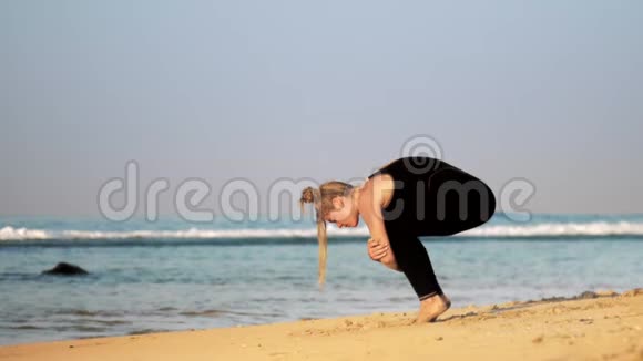 运动女孩在海边做前向折叠瑜伽姿势视频的预览图