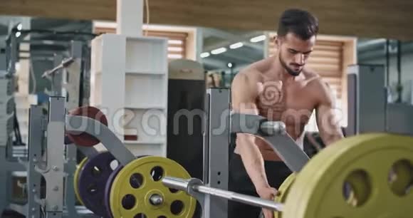 一个英俊的肌肉发达的男人在酒吧里增加了体重因为他正在健康和锻炼视频的预览图