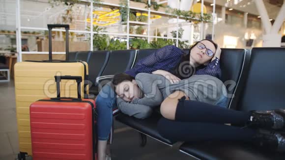 女人和女儿一起睡在机场的椅子上等待出发视频的预览图