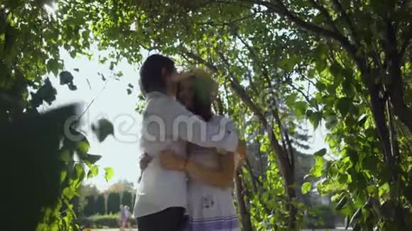 快乐的年轻夫妇拥抱在公园或花园里户外休闲与自然接轨享受阳光灿烂的一天视频的预览图