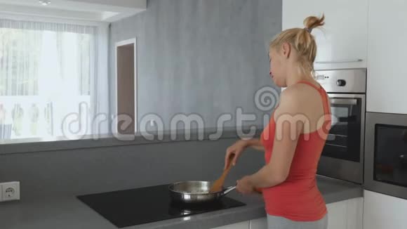 在炉子前准备的女人平底锅配切好的洋葱女人用木铲搅动洋葱视频的预览图