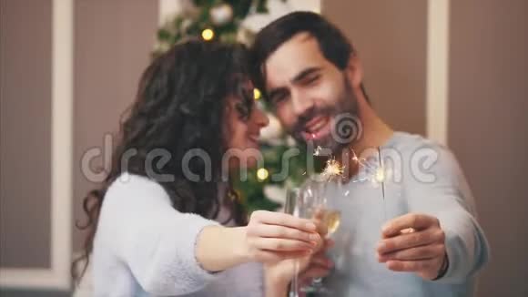 在节日的气氛中可爱的夫妇模糊的特写站在孟加拉灯和香槟触摸鼻子视频的预览图