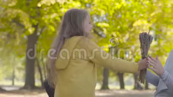 两个可爱的白种人小妹妹给妈妈送花亲吻她漂亮的金发卷发女人在度假视频的预览图