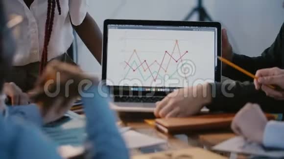 特写镜头男性上班族双手在多民族商业团队会议上笔记本电脑屏幕上显示营销图视频的预览图