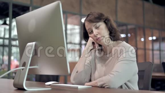 疲惫的老年妇女在工作中快速打盹视频的预览图