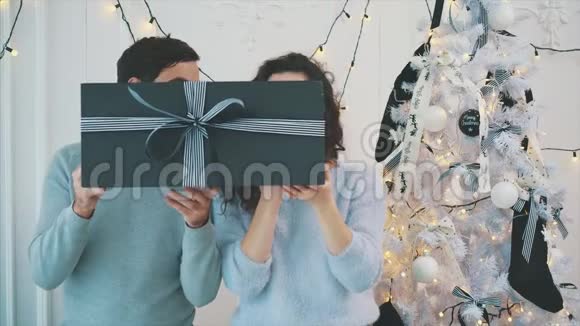 男孩和女孩拿着巨大的灰色礼品盒与条纹流光并做脸视频的预览图