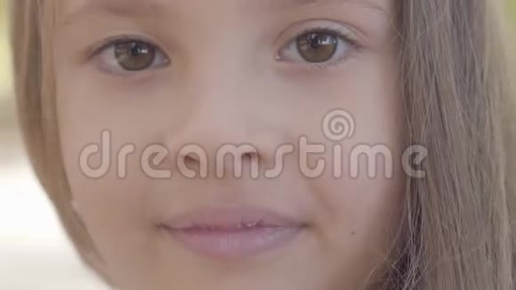 一个小可爱的棕色眼睛女孩的特写黑发女孩对着镜头微笑可爱的白种人儿童视频的预览图