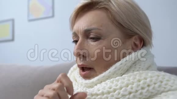 戴围巾咳嗽在家吃药片感冒或感冒的老年女性视频的预览图