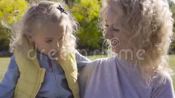 金发白种人女人的肖像卷发手上拿着小漂亮女孩开心的微笑母女视频的预览图
